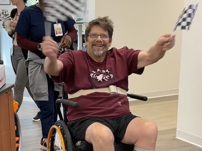 Photo of John Wilmes holding checkered flags at SSM Neuro Transitional Center.